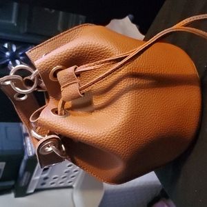 Small brown pursecrossbows with gold strap to be worn as crossbody.